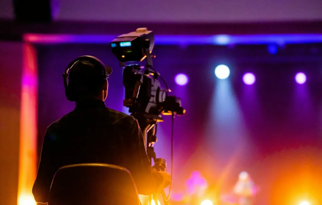 Camera operator filming a stage with colourful lights